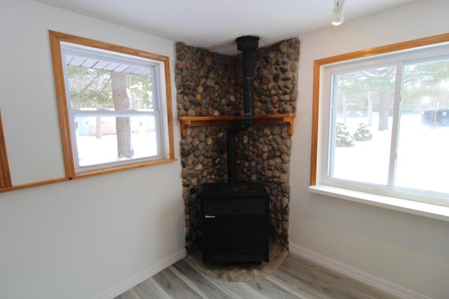 living room featuring a wood stove, light wood-style flooring, and baseboards