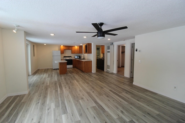 unfurnished living room featuring a textured ceiling, light wood-style floors, and a sink