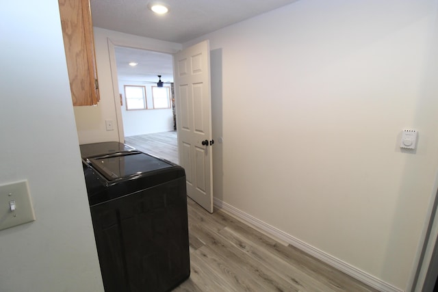 laundry room with baseboards, light wood-style floors, and washing machine and clothes dryer