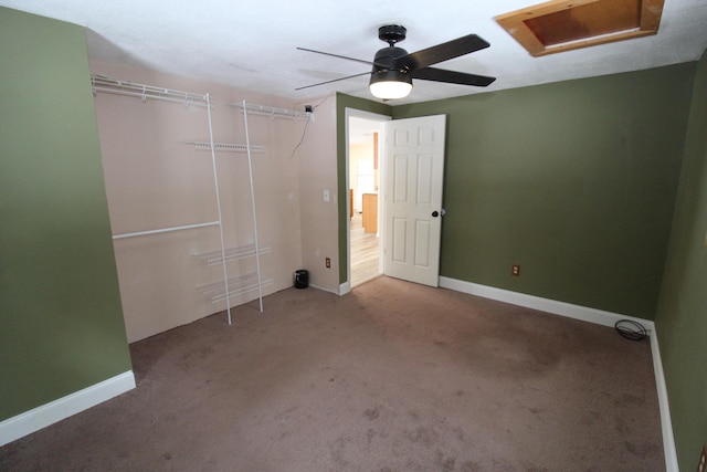 unfurnished bedroom featuring attic access, carpet, baseboards, and ceiling fan