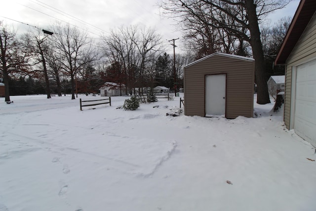 snowy yard with an outdoor structure, a storage unit, and a garage