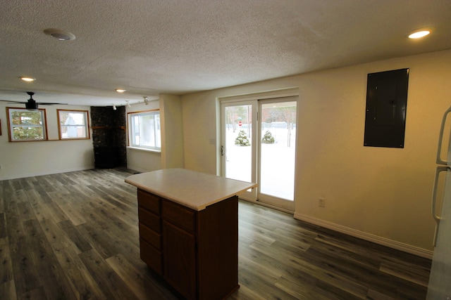 kitchen featuring electric panel, a textured ceiling, dark wood finished floors, light countertops, and baseboards