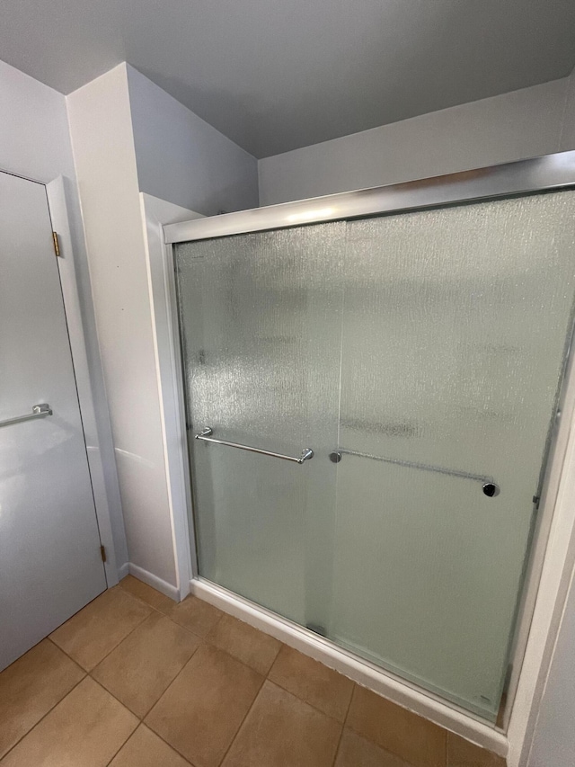 full bathroom with a stall shower and tile patterned flooring