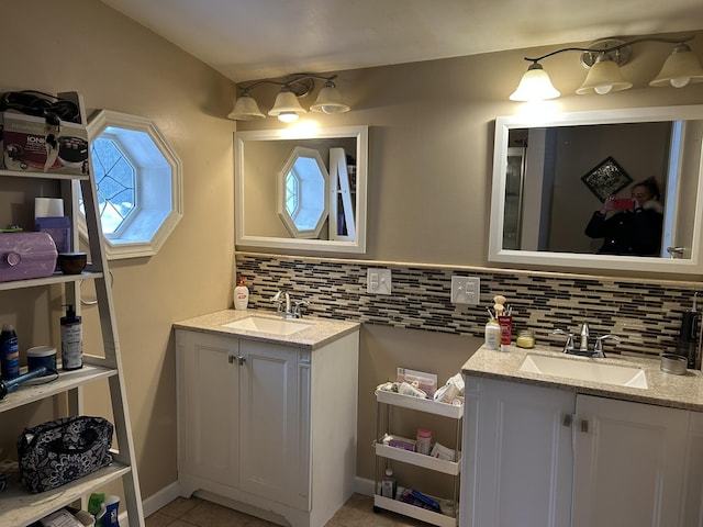 bathroom featuring two vanities, tasteful backsplash, and a sink