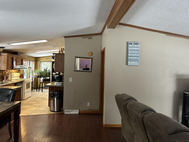 interior space with light wood-type flooring, a textured ceiling, visible vents, and ornamental molding