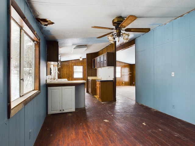 kitchen featuring vaulted ceiling, a peninsula, dark wood-style floors, a ceiling fan, and a sink