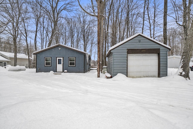 snow covered garage with a detached garage