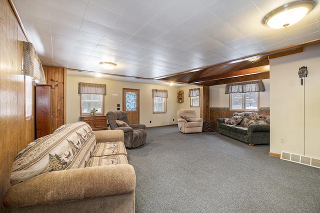 living room featuring wooden walls, carpet flooring, and visible vents