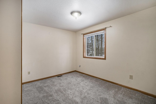carpeted spare room featuring baseboards, visible vents, and a textured ceiling