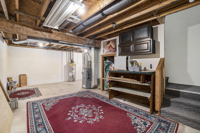 unfinished basement featuring stairs, heating unit, and water heater