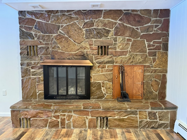 details featuring a fireplace, a baseboard heating unit, and wood finished floors