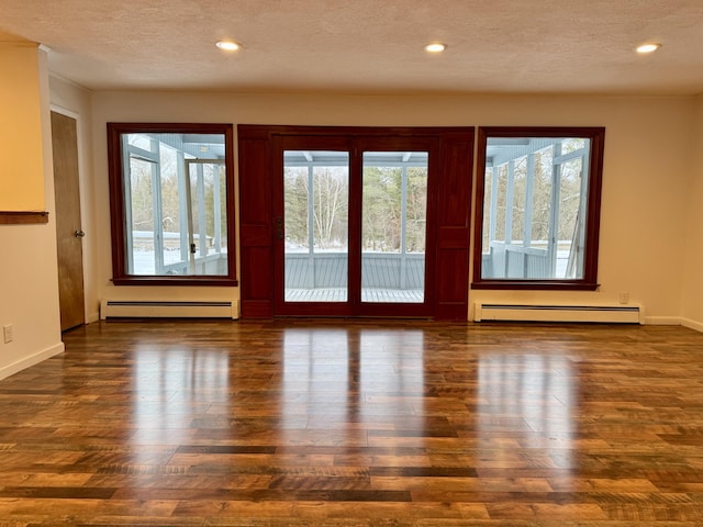 empty room featuring a textured ceiling, wood finished floors, and a baseboard radiator