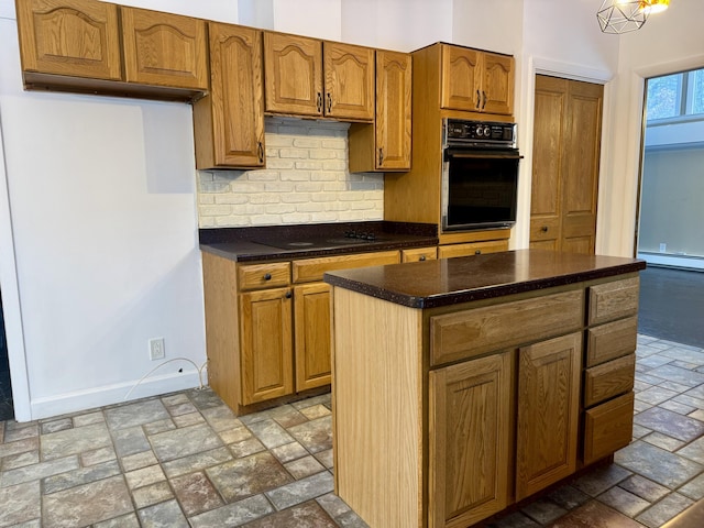 kitchen with dark countertops, backsplash, baseboards, stone tile floors, and black appliances