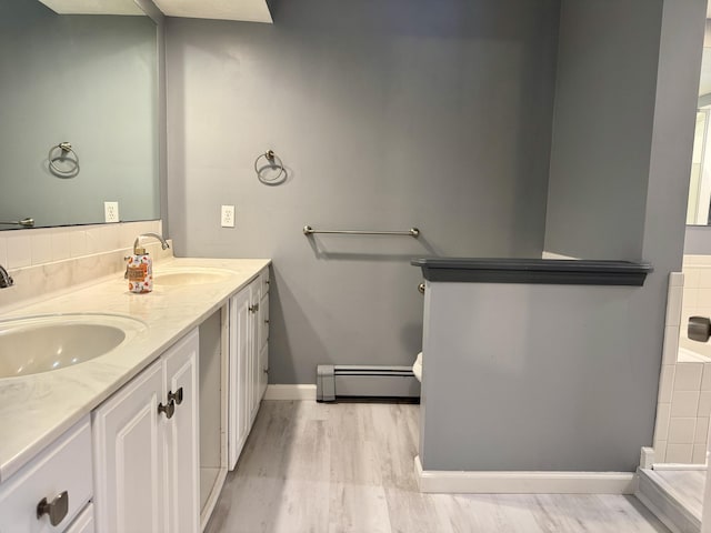 bathroom with a sink, baseboard heating, and wood finished floors