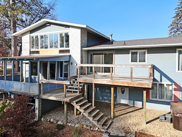 back of house with brick siding, stairway, roof with shingles, a deck, and a sunroom