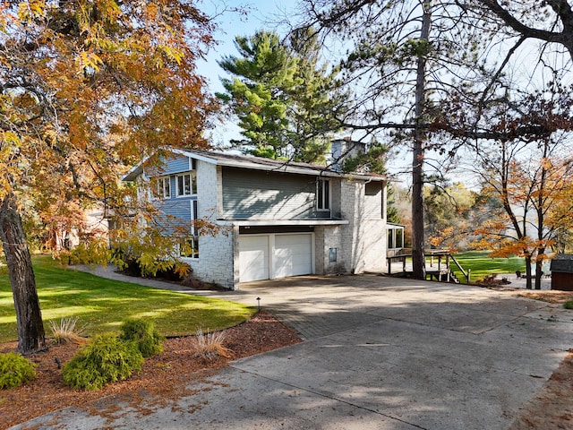 view of side of property with a yard, brick siding, a garage, and driveway