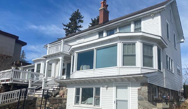 exterior space with stairway, a balcony, and a chimney