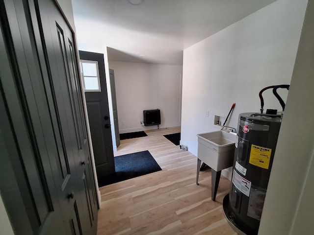 foyer entrance featuring electric water heater, light wood-style floors, and baseboards