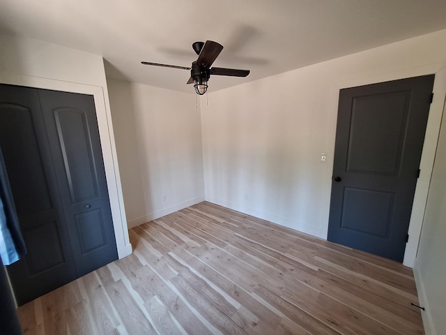 unfurnished bedroom with light wood-type flooring, a closet, baseboards, and ceiling fan