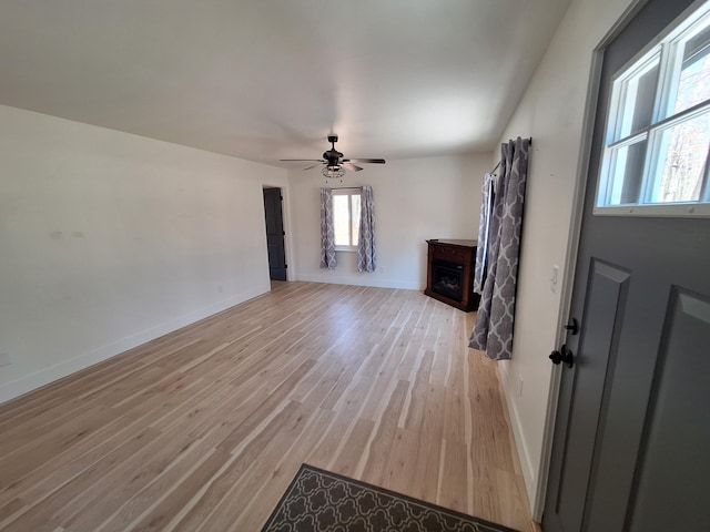 unfurnished living room featuring baseboards, ceiling fan, and light wood finished floors