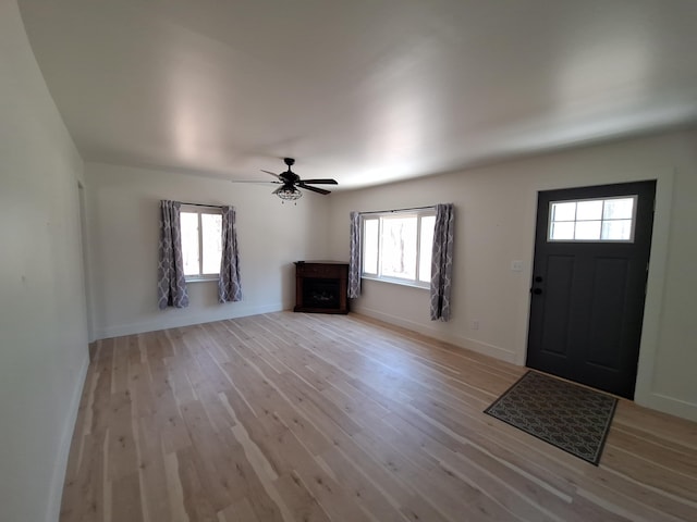 foyer entrance featuring light wood-style floors, ceiling fan, and baseboards