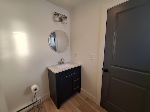 bathroom with wood finished floors, vanity, baseboard heating, and baseboards