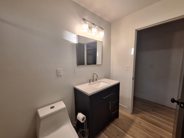 bathroom featuring wood finished floors, toilet, vanity, and baseboards