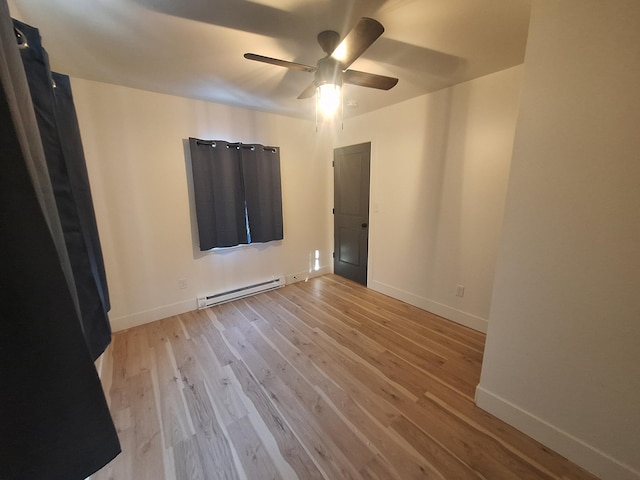 unfurnished room with baseboard heating, wood finished floors, a ceiling fan, and baseboards
