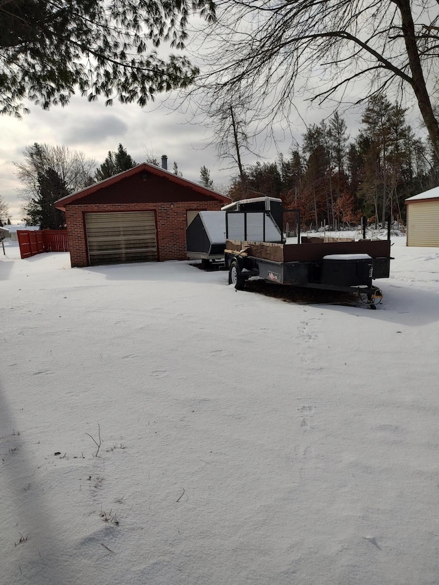 snow covered garage with fence