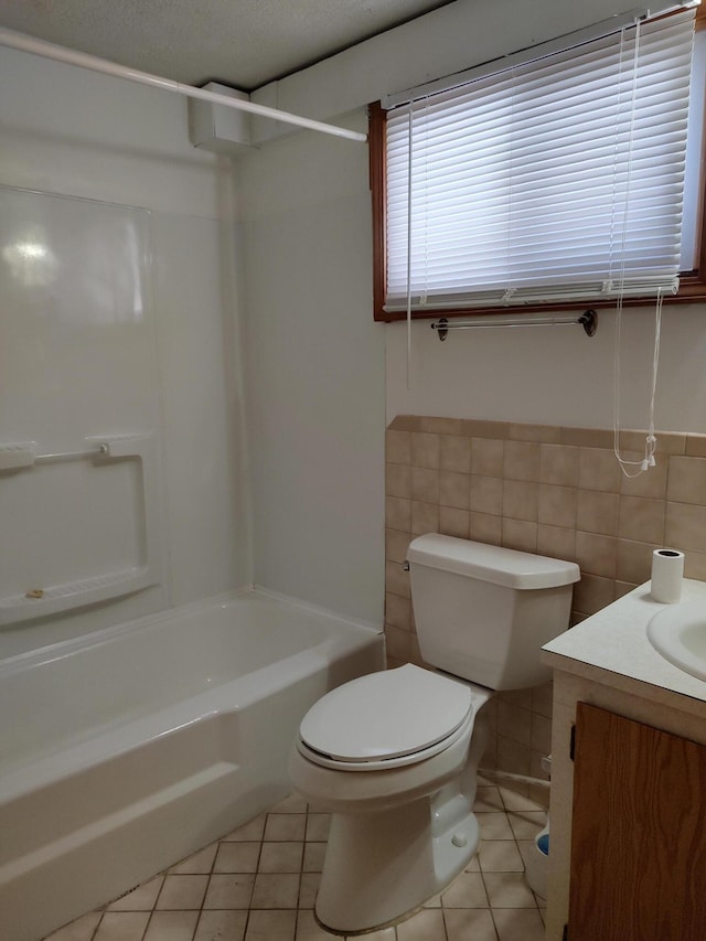 bathroom featuring tile patterned floors, a wainscoted wall, toilet, tile walls, and vanity