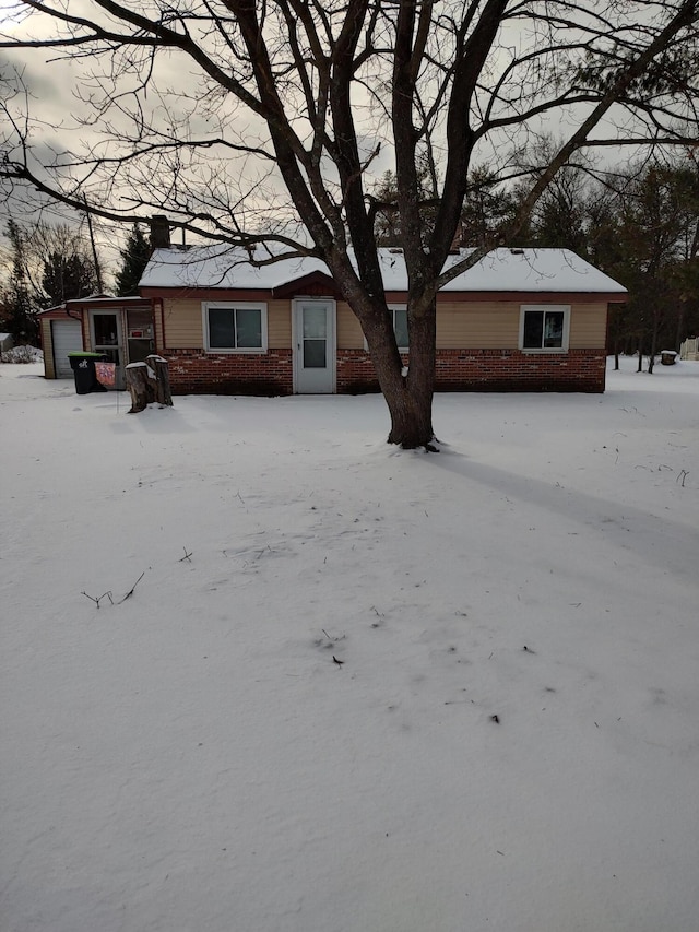 view of front of house featuring an outdoor structure, an attached garage, and brick siding