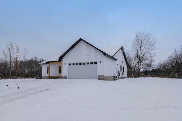 snow covered property featuring an attached garage