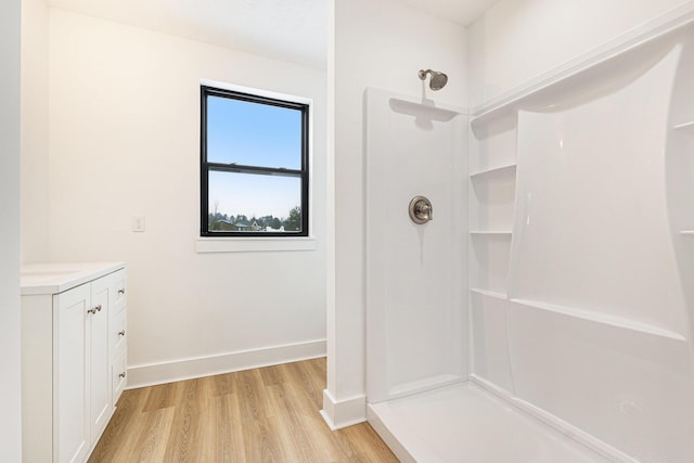 full bathroom with vanity, wood finished floors, a shower, and baseboards