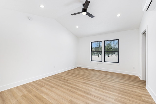 empty room with a ceiling fan, baseboards, an AC wall unit, vaulted ceiling, and light wood-type flooring