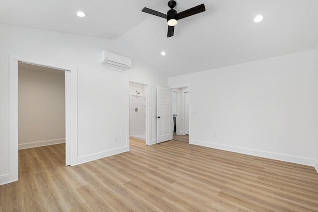 interior space with lofted ceiling, baseboards, light wood finished floors, and a wall mounted AC