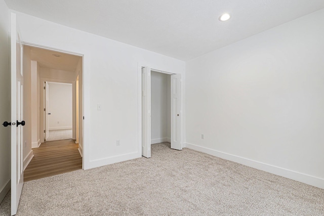 unfurnished bedroom with recessed lighting, a closet, baseboards, and light colored carpet