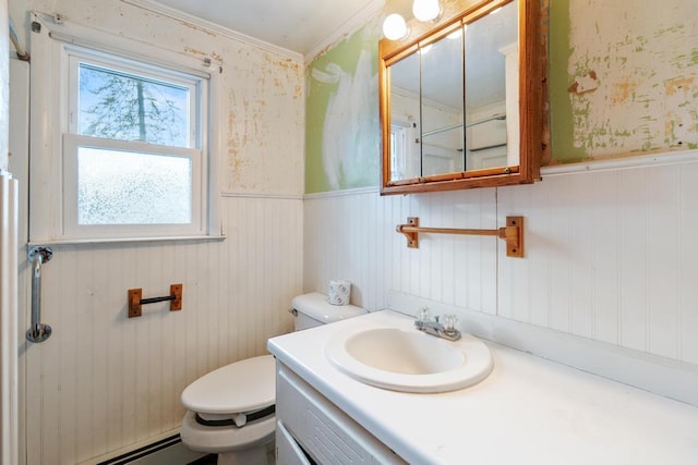 bathroom with a baseboard radiator, toilet, wainscoting, and wallpapered walls