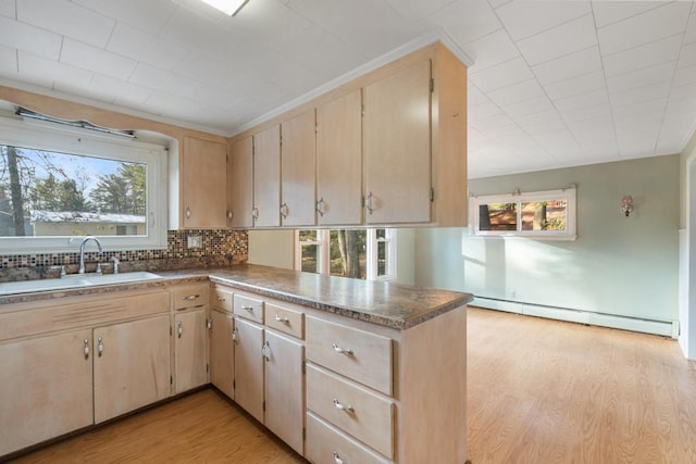 kitchen with light brown cabinets, a sink, tasteful backsplash, light wood-style floors, and baseboard heating