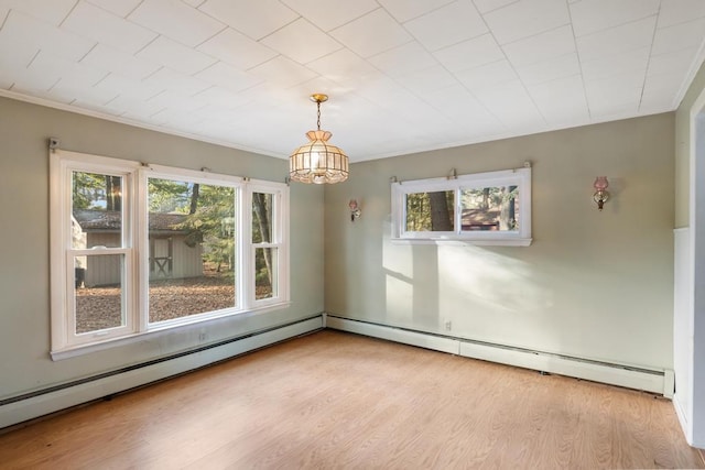 spare room featuring baseboard heating, ornamental molding, and wood finished floors