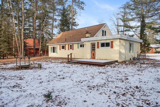 snow covered property featuring a wooden deck and a chimney