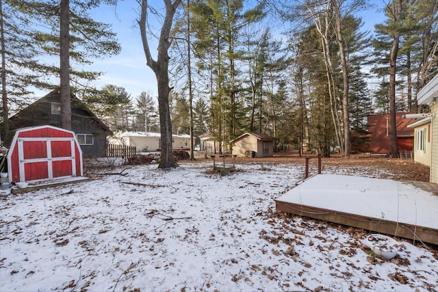 yard layered in snow with a storage unit and an outdoor structure