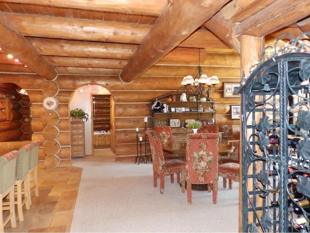 wine area with arched walkways, beamed ceiling, carpet flooring, a chandelier, and rustic walls