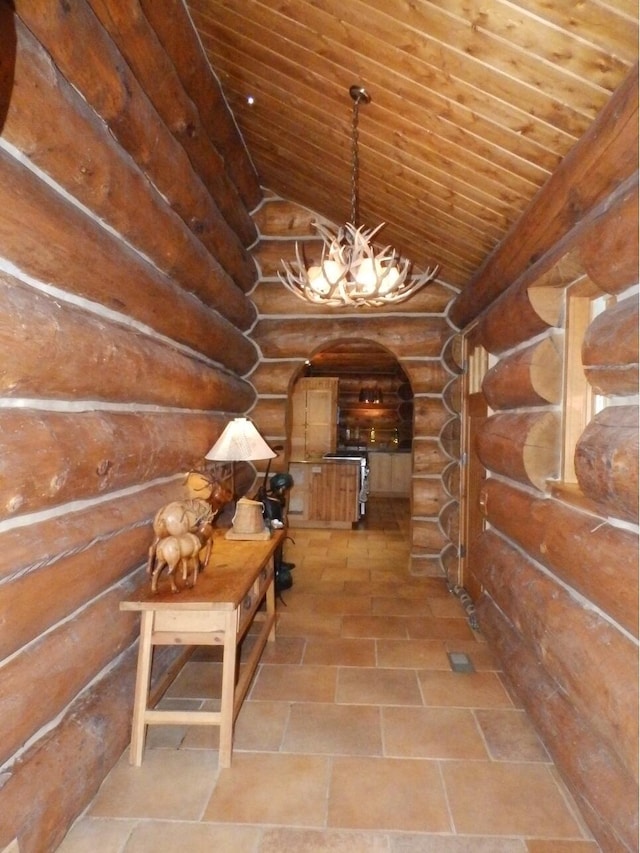 hallway with an inviting chandelier, lofted ceiling, arched walkways, wood ceiling, and rustic walls