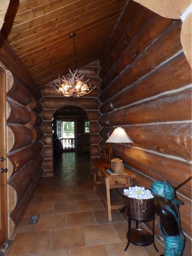 hallway with arched walkways, vaulted ceiling, wood ceiling, a notable chandelier, and rustic walls