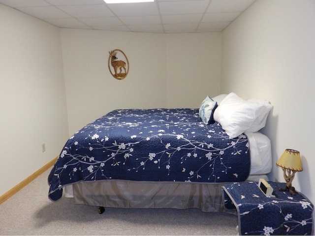 bedroom with a drop ceiling, carpet flooring, and baseboards