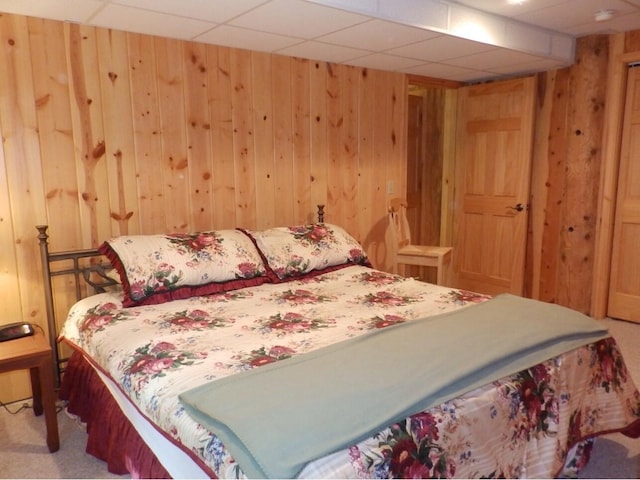 bedroom featuring wood walls, a paneled ceiling, and carpet floors