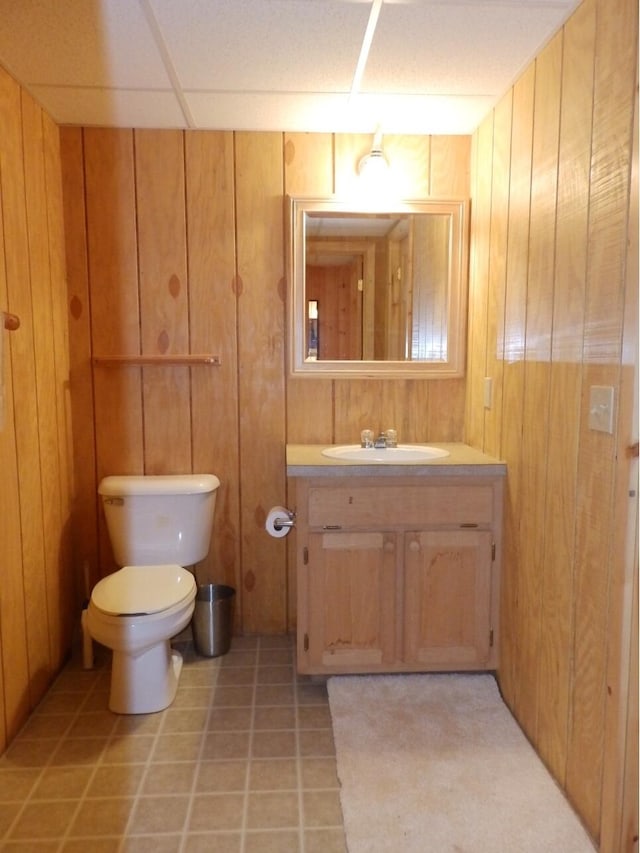 bathroom featuring vanity, toilet, tile patterned flooring, and wood walls