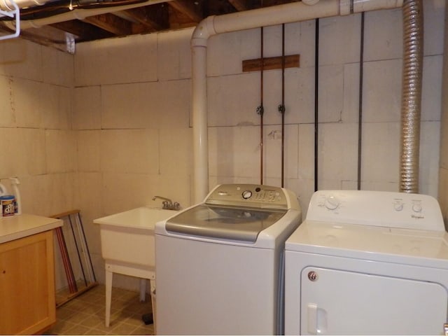 washroom featuring laundry area, washing machine and dryer, and a sink