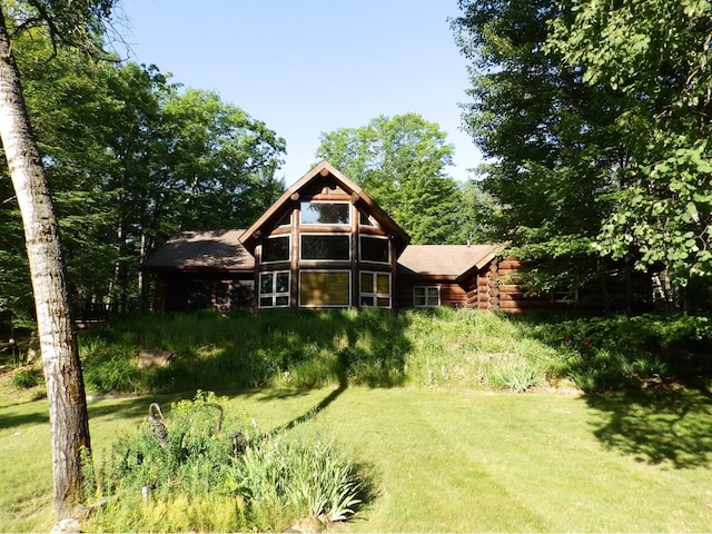 back of property with log exterior and a lawn