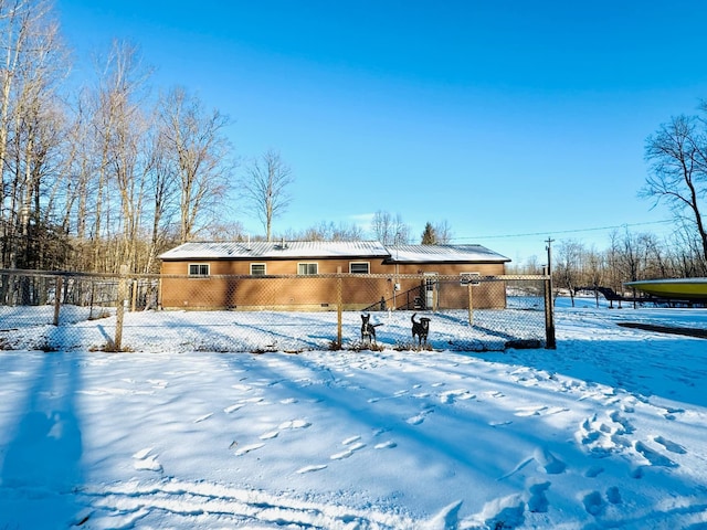 snow covered rear of property with a fenced front yard